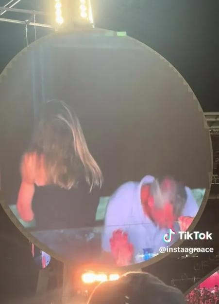 A large screen showing a man and woman embracing at a Coldplay concert.