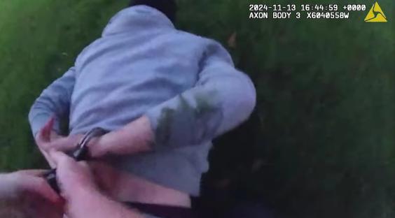 Police officer handcuffing a suspect on the ground.
