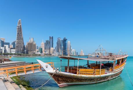 Doha skyline with a traditional boat in the foreground.