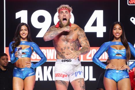 Jake Paul at a weigh-in, flanked by two women.