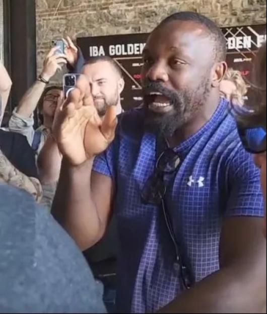 A man speaking animatedly to a crowd.