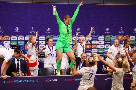 Mary Earps celebrates on a table with her England teammates after winning the UEFA Women's Euro 2022.