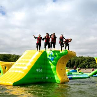 Five people jumping off an inflatable water park structure.