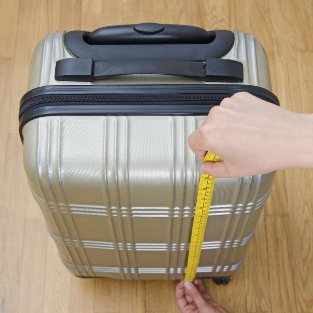 Measuring carry-on luggage with a tape measure.