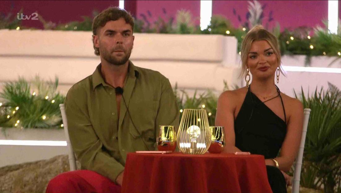 A man and woman sit at a table during a date.