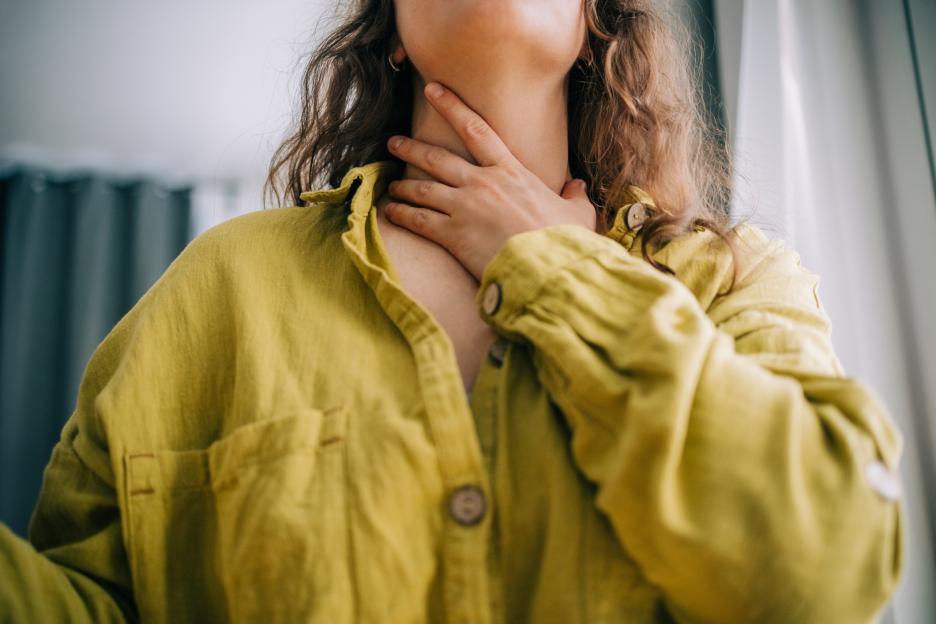 Woman holding her throat, experiencing a sore throat.