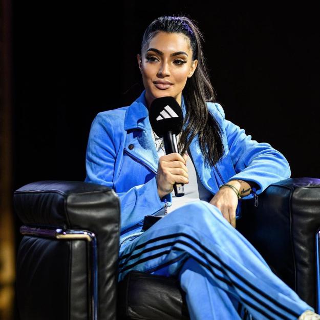 Woman in blue Adidas tracksuit holding a microphone.