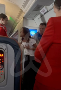A passenger arguing with flight attendants on an airplane.