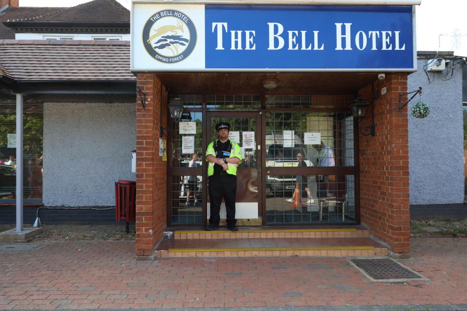 Police officer standing outside The Bell Hotel during a protest.
