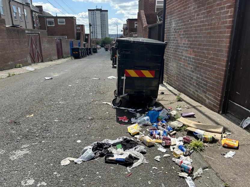 Litter and trash in a narrow alleyway.