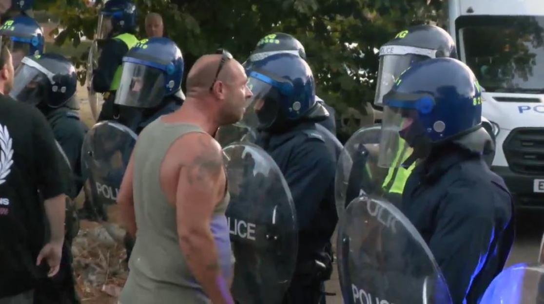 Riot police confronting a man.