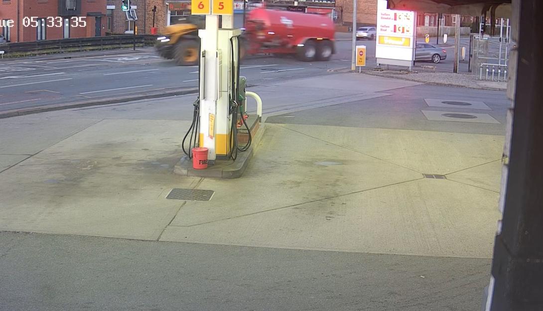 Screenshot of a gas station with a fuel tanker and cars driving by.