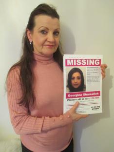 Woman holding missing person poster of her daughter.