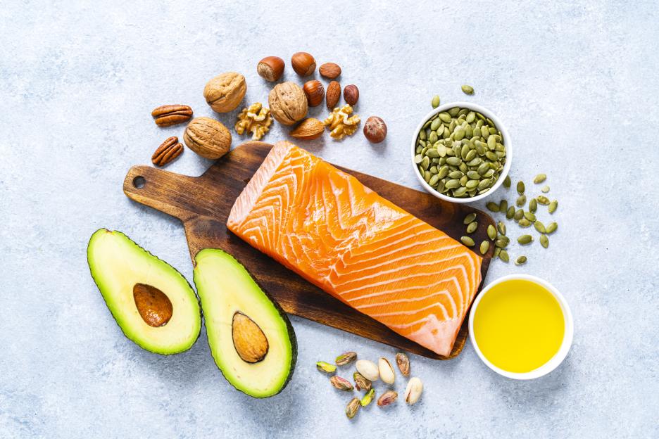 Overhead view of salmon, avocados, nuts, seeds, and olive oil.