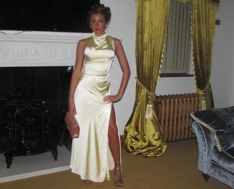 a woman in a long dress stands in front of a fireplace