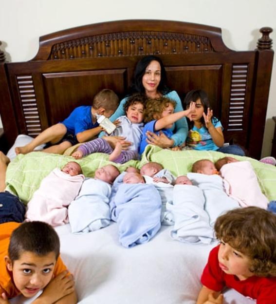 Woman with her 14 children on a bed.