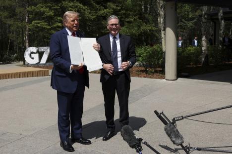 President Trump and Prime Minister Starmer holding a signed trade agreement.