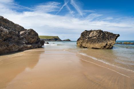 Sandy beach with rocks and ocean.
