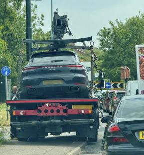 A dark-colored Porsche Macan on a tow truck.