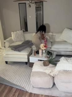 Person arranging pillows on a white sectional sofa.