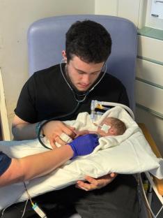 Man holding premature baby receiving medical care.