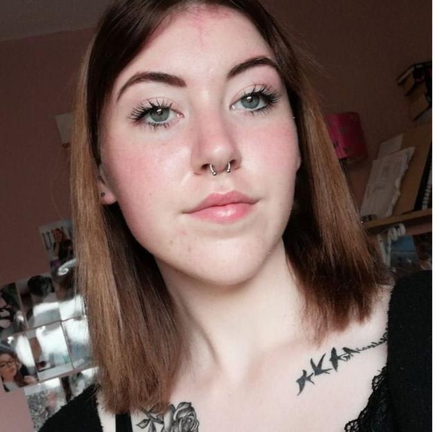 Photo of a young woman with septum piercing and tattoos.