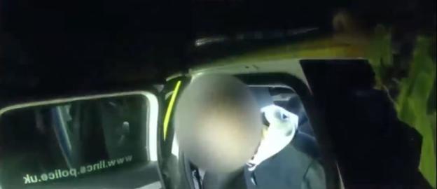 Bodycam footage of a person in the back of a police car.