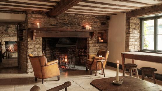 Cozy stone room with fireplace and leather armchairs.