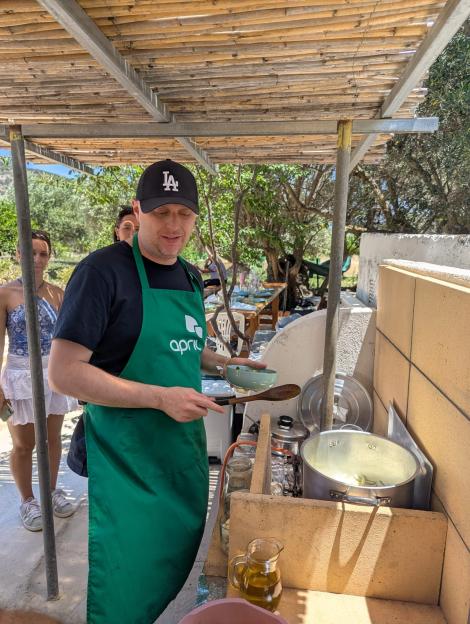 Man in apron cooking outdoors in Crete.