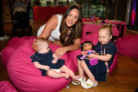 A woman with two young children sitting on pink beanbag chairs.