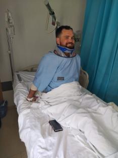 Man in hospital bed wearing neck brace.