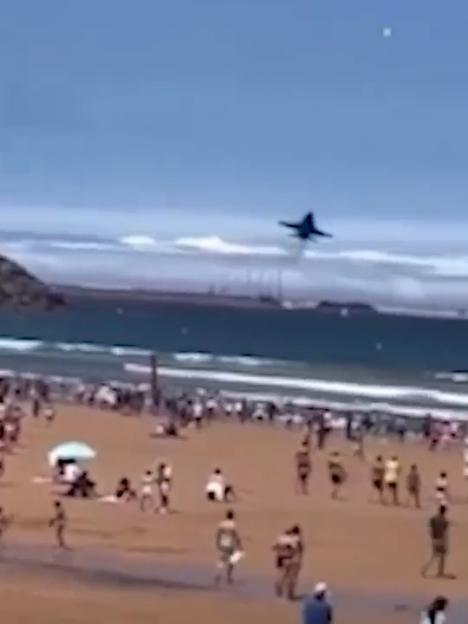 Jet flying low over a crowded beach.