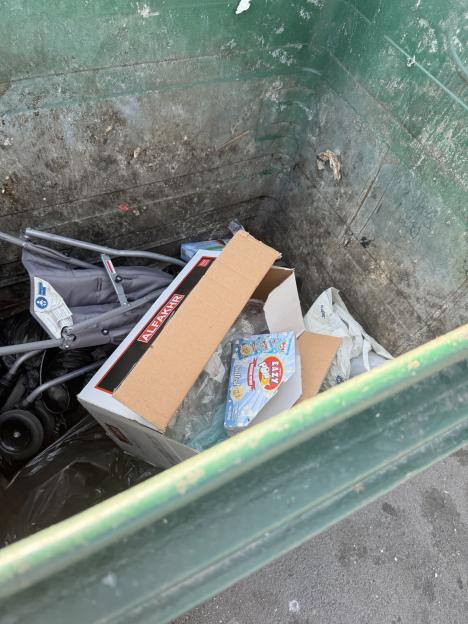 Stroller and boxes in a dumpster.