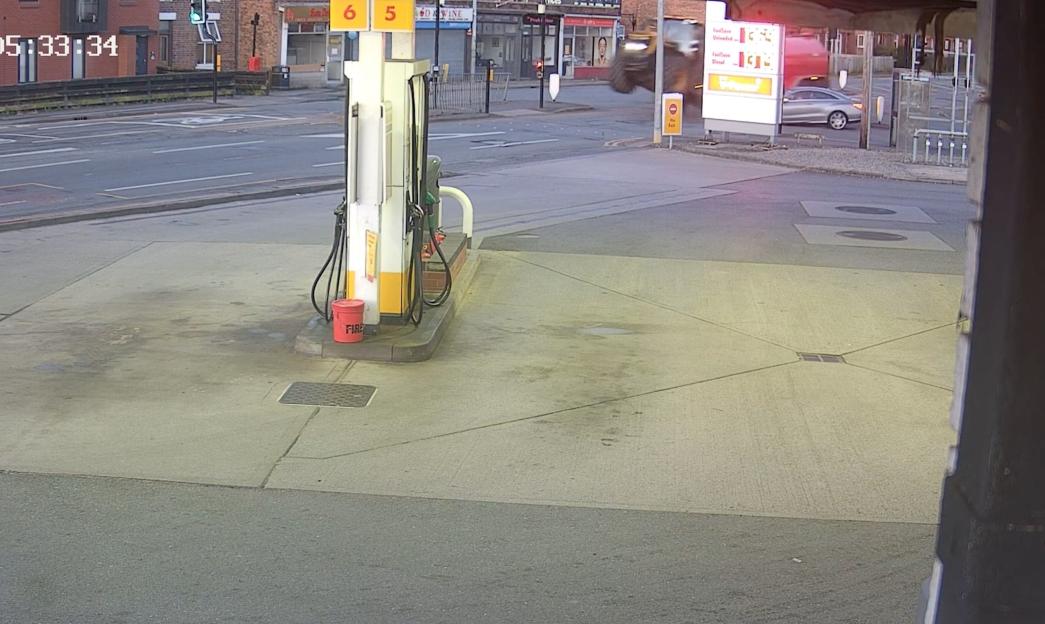 Screenshot of a gas station with a vehicle driving away.