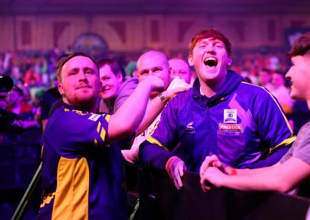 Luke Littler and Morgan Burtwistle celebrating a darts match victory.
