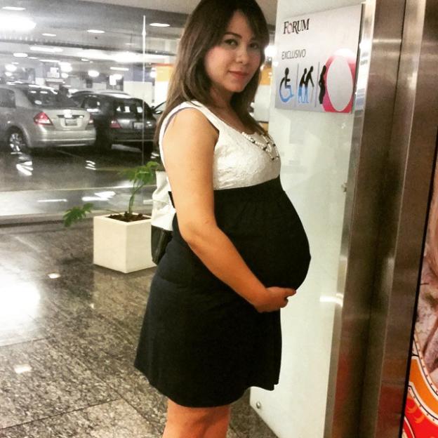 Pregnant woman in a dress standing near an elevator.