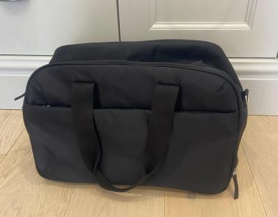 Black duffel bag on a light wood floor.