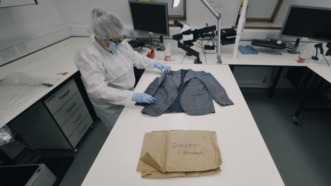 Forensic scientist examining a preserved jacket for DNA evidence.