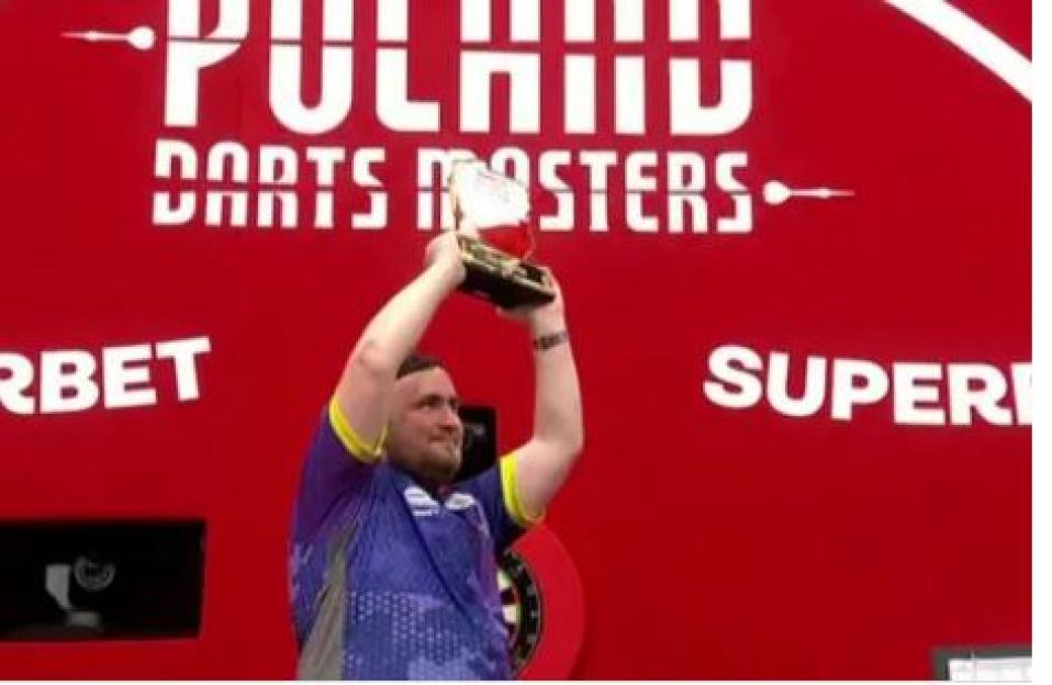 Darts player holding up a trophy at the Polish Darts Masters.