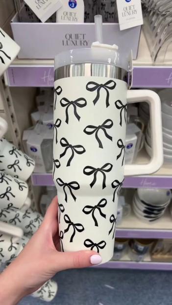 Person holding a white tumbler with black bows.