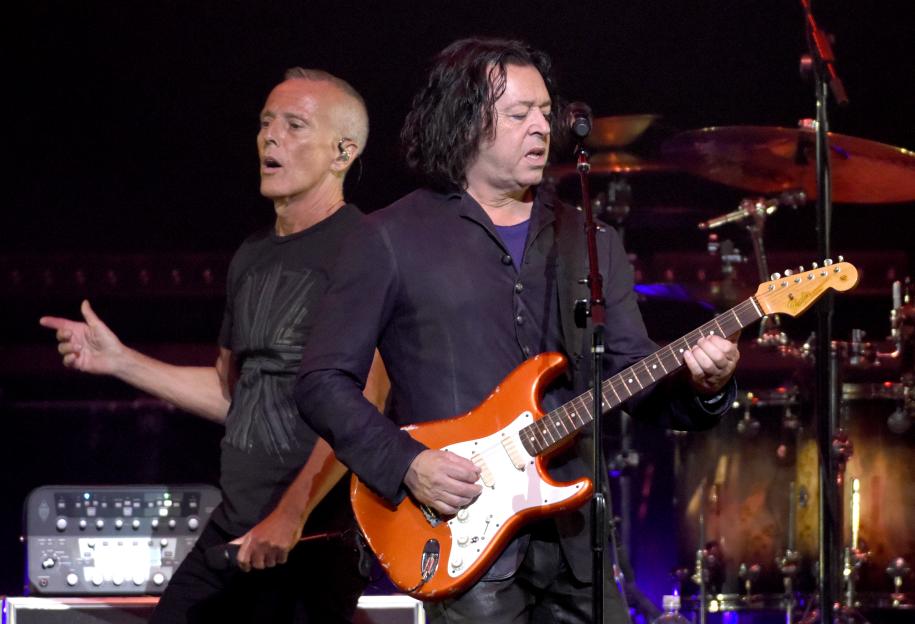 Roland Orzabal of Tears for Fears playing guitar on stage.