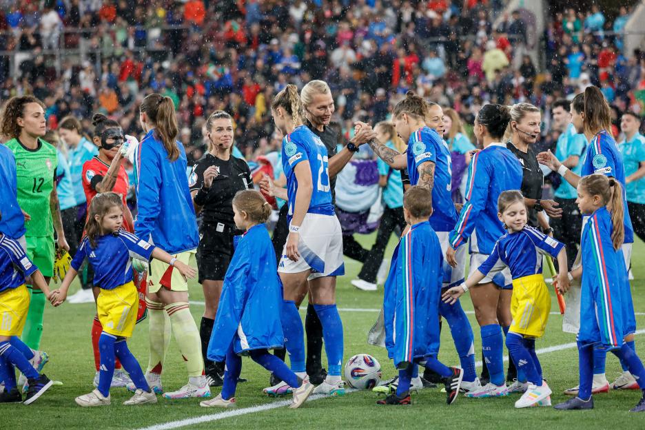 Referees greet the Italian women's soccer team before a match.
