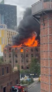 Large fire engulfing a brick building in Manchester.