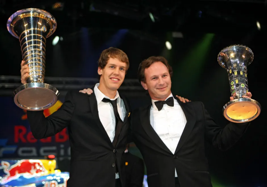 Two men in tuxedos holding trophies.
