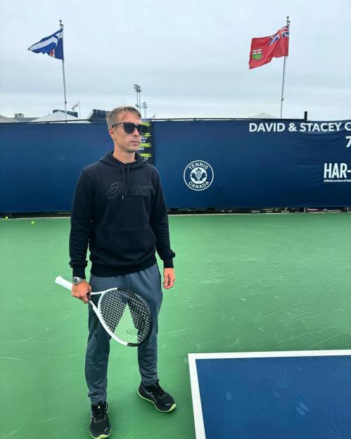 Man holding tennis racket on tennis court.