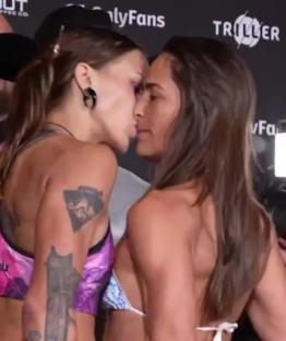 Two women kissing at a fight event.