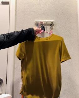 Mustard yellow shirt hanging on a hook.