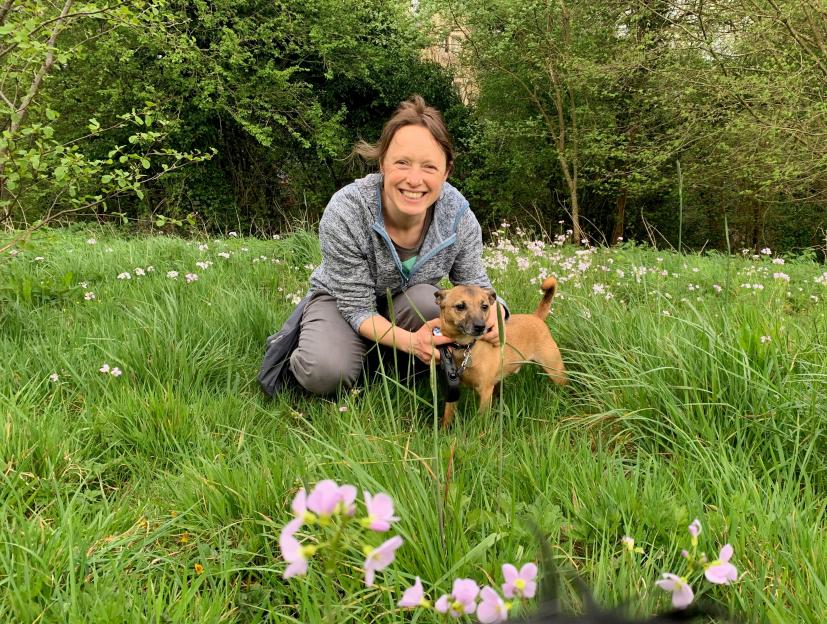Woman kneeling in a field with her dog.