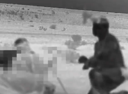 Thermal image of a person crouching near another blurred figure.
