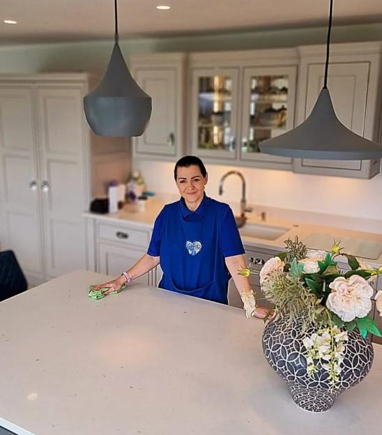 A cleaner wiping down a kitchen counter.